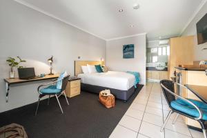 a hotel room with a bed and a desk and chairs at Alara Motor Inn in Mackay