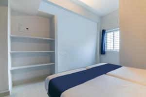 a white bedroom with a bed and a window at Hotel O Maraimalai Nagar in Singapperumālkovil