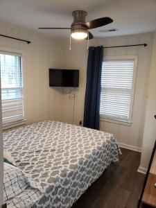a bedroom with a bed and two windows at Kure Beach Cottage-Fully Updated--1 block- welcome dogs for modest fee in Kure Beach