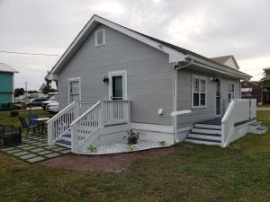 a small white house with a porch and stairs at Kure Beach Cottage-Fully Updated--1 block- welcome dogs for modest fee in Kure Beach