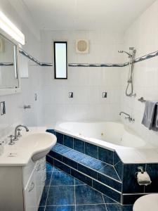 a white bathroom with a tub and a sink at Beach Shack in Bargara in Bargara