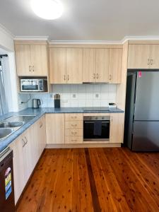 a kitchen with wooden cabinets and a black refrigerator at Beach Shack in Bargara in Bargara