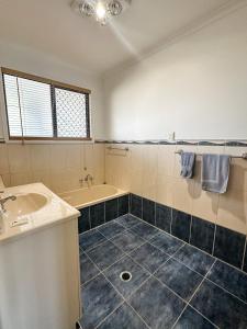 a bathroom with a tub and a sink and a bath tub at Beach Shack in Bargara in Bargara