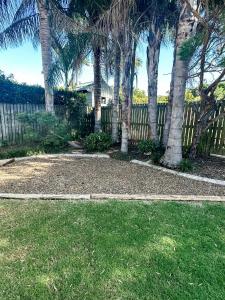 a yard with palm trees and a fence at Beach Shack in Bargara in Bargara