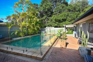 una piscina con paredes de cristal y palmeras en Driftwood Beach home, en Kawana Waters