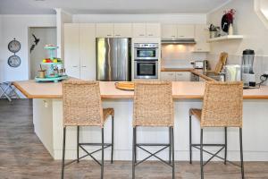 una cocina con encimera con 3 taburetes en Driftwood Beach home, en Kawana Waters