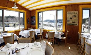 a dining room with tables and chairs and windows at Hotel - Motel Georges in Tadoussac