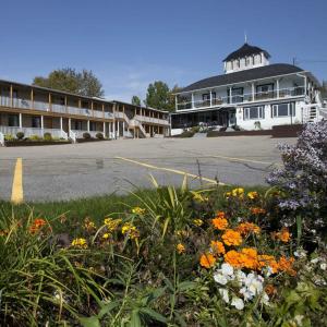 a building with a lot of flowers in front of it at Hotel - Motel Georges in Tadoussac