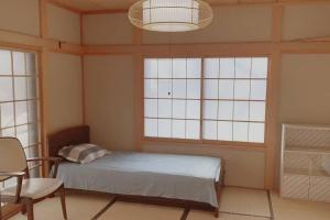 a bedroom with a bed and a chair and windows at 一番館※温泉街に近く、心が落ち着く別荘地同樺順荘 in Kusatsu