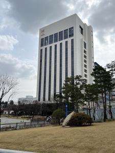 a tall white building with trees in front of it at The Marevo in Suwon