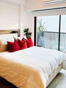 1 dormitorio con 1 cama grande con almohadas rojas en Estudio en Palermo con balcon y edificio con amenities en Buenos Aires