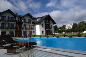 a swimming pool in front of a building at Perla Mare Apartamenty in Krynica Morska