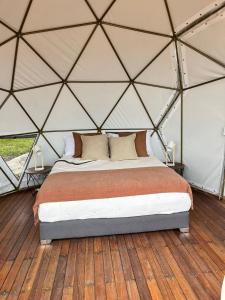 a bed in a yurt with a wooden floor at Glamping Altos De Hayuelos in Paipa