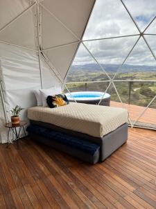 a bedroom with a bed in a tent with a hot tub at Glamping Altos De Hayuelos in Paipa