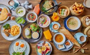 a table with many plates of food on it at Kimpton Maa-Lai Bangkok, an IHG Hotel in Bangkok