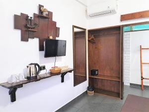 um quarto com uma televisão e uma prateleira na parede em Katara Gili, Boutique Rooms and Bungalows em Gili Trawangan