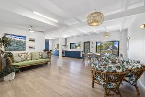 uma sala de estar com um sofá, uma mesa e cadeiras em Pandanus On Emerald em Emerald Beach