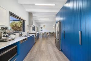 uma cozinha com armários azuis e um frigorífico azul em Pandanus On Emerald em Emerald Beach
