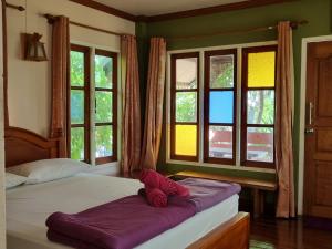 um quarto com 2 camas com lençóis roxos e janelas em Hello Sichang Bungalow em Ko Si Chang