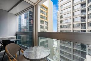 un balcone con tavolo, sedie e ampia finestra di Stylish CBD apt in prime location w Balcony#TF2508 a Melbourne