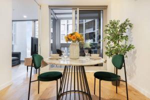 tavolo da pranzo con sedie verdi e vaso con fiori di Stylish CBD apt in prime location w Balcony#TF2508 a Melbourne