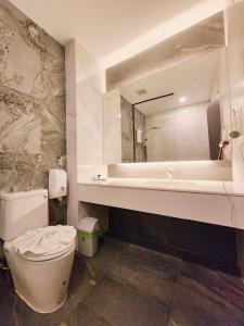 een badkamer met een toilet, een wastafel en een spiegel bij R2 Hotel in Nakhon Phanom