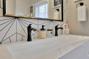 a bathroom sink with two faucets and a mirror at Hawksbill Home~Hot Tub~Dog Friendly~Modern~Water Front Porch in Luray
