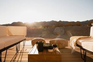 a patio with two couches and a coffee table with a rainbow at Blazing Star Estate - 400 feet from JT Park in Joshua Tree