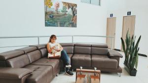Una donna seduta su un divano con un bambino in braccio di Apto con Piscina a 5min del Parque Nacional Del Café a Montenegro
