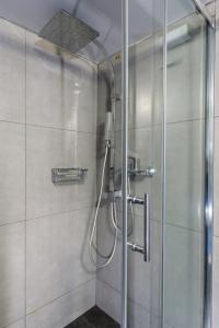 La salle de bains est pourvue d'une douche avec une porte en verre. dans l'établissement Armoniko, à Athènes