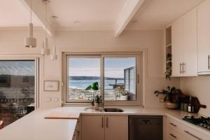 a kitchen with a large window with a view of the ocean at Olga and Alma - The Coastal Retreat in Pambula Beach