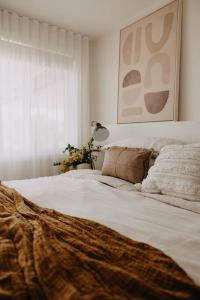 Una cama blanca con una manta en un dormitorio en Olga and Alma - The Coastal Retreat, en Pambula Beach