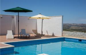 a swimming pool with two chairs and an umbrella at Nice Home In Baena With Outdoor Swimming Pool in Baena