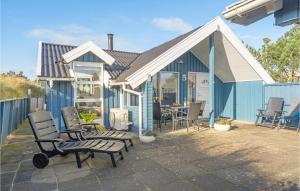 a blue house with chairs and a table on a patio at Åbo in Klitmøller