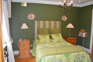 1 dormitorio con 1 cama con paredes verdes y 2 lámparas en Beechwood Country House, en Malahide