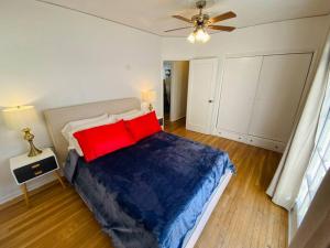 洛杉磯的住宿－Cozy 1,400sq ft 2BR+2BA WeHo Gated Home，一间卧室配有一张带红色枕头的床和吊扇