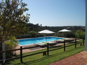 a swimming pool with two chairs and umbrellas at Casas da Bica - Homes with Soul in Mira Olhos