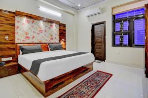 a bedroom with a large bed with a wooden headboard at Hotel Tejesvi in Jaipur