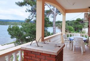 une terrasse couverte avec une table et des chaises et une vue sur l'eau dans l'établissement Apartments Josef - sea view, à Veli Rat