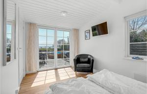 ein Schlafzimmer mit einem Bett und einem Stuhl sowie einem Balkon in der Unterkunft Beautiful Home In Prst With House Sea View in Stavreby