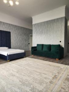 ein Wohnzimmer mit einem grünen Sofa und einem Bett in der Unterkunft Hotel Inju in Borovoye