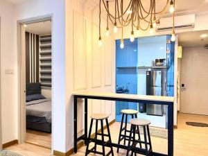 eine Küche mit zwei Barhockern und ein Zimmer mit einem Bett in der Unterkunft Grand Suite @ The Wave Residence-Cozy 2-BR Retreat: AC, Street Views & Games in Malakka