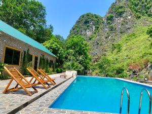 a swimming pool with lounge chairs and a mountain at Hang Lan Bungalow in Ninh Binh
