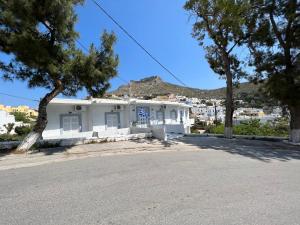 a white building with trees in front of a street at Spanos Apartments - Panteli in Panteli