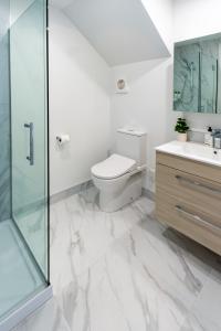 a white bathroom with a toilet and a glass shower at The Tranquil Terrace - Zen zone 2 bed 2 bath in Christchurch