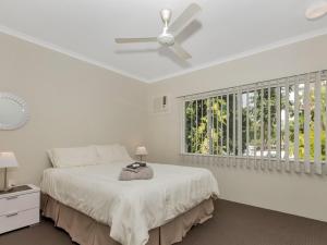 a white bedroom with a bed and a ceiling fan at The Moorings at Yorkeys Knob in Yorkeys Knob