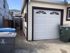 een garage met een witte garagedeur en een vuilnisbak bij SFO New Comfortable Studio in San Bruno