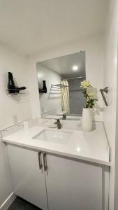 a white bathroom with a sink and a mirror at Unit #204 Cozy Mountain View 2BR in Canmore Downtown in Canmore