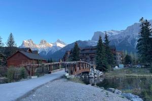 a bridge over a river with mountains in the background at Unit #204 Cozy Mountain View 2BR in Canmore Downtown in Canmore