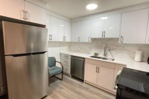 a kitchen with white cabinets and a stainless steel refrigerator at Unit #204 Cozy Mountain View 2BR in Canmore Downtown in Canmore +10 photos